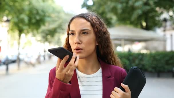 一个拉丁女商人在街上走着的智能手机上使用语音识别系统的人物形象 — 图库视频影像