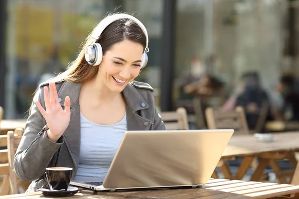 幸せな女性身に着けています無線ヘッドセットビデオコーリング上のラップトップに座ってカフェテラス — ストック写真