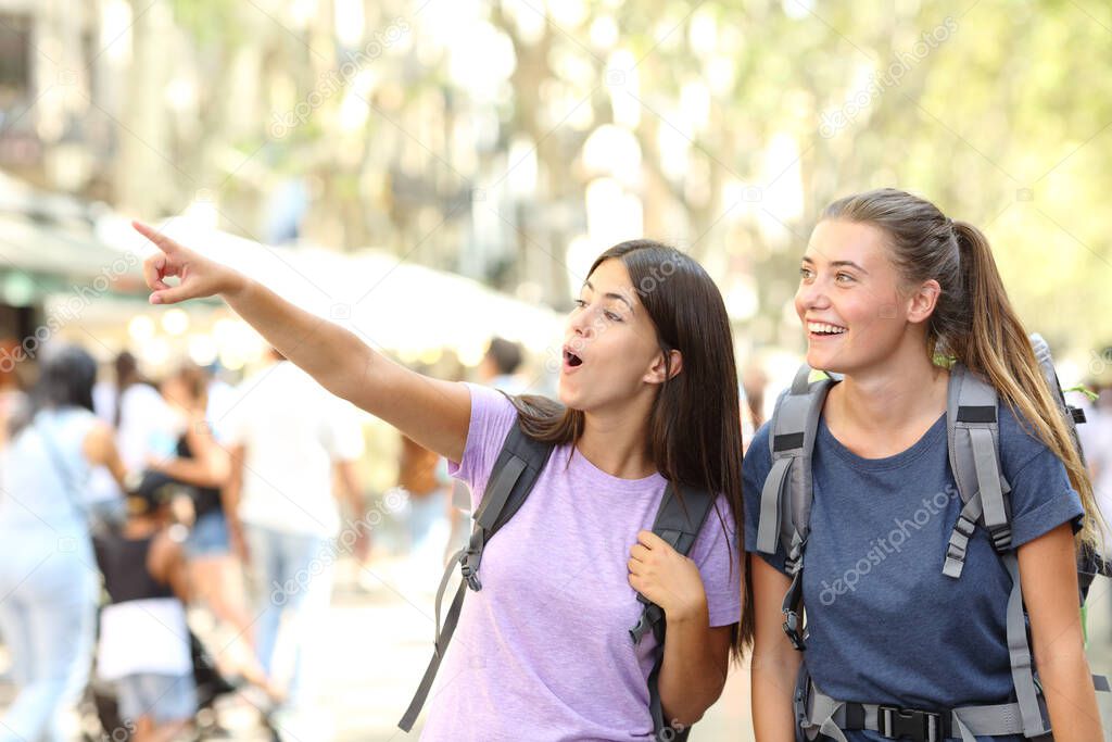 Two surprised backpackers sightseeing in the street finding and pointing landmark