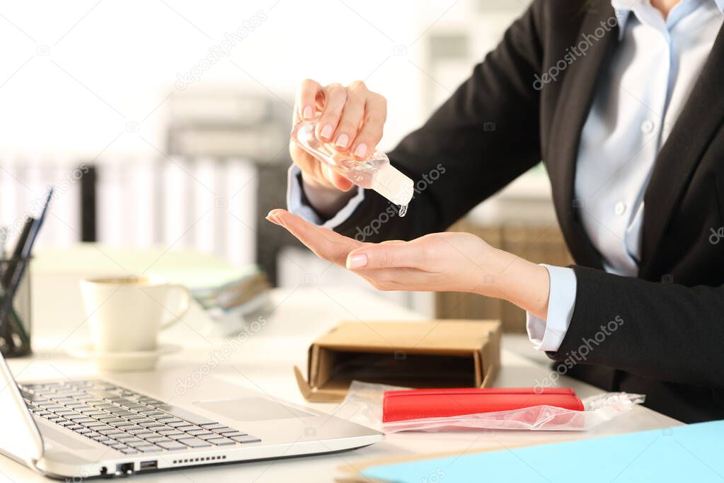 Close up of business woman with opened package over the desk sanitizing hands in the office
