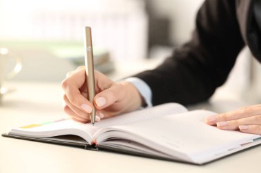 Yönetici kadın ellerinin ofiste gündemle ilgili notlar yazmasını kapat.