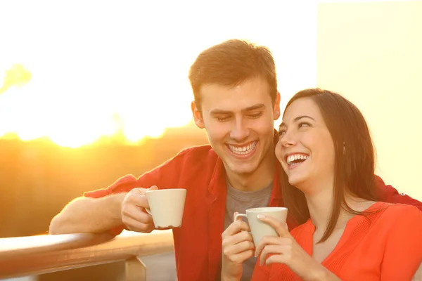 Szczęśliwa Para Przytula Trzymając Filiżanki Kawy Ciesząc Się Zachodzie Słońca — Zdjęcie stockowe