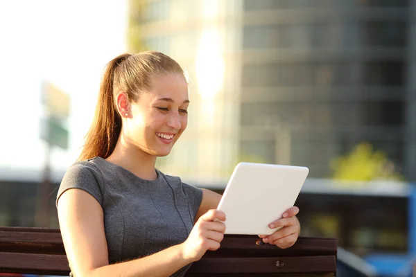 快乐的女人坐在公园的长椅上在线观看平板电脑上的视频 — 图库照片