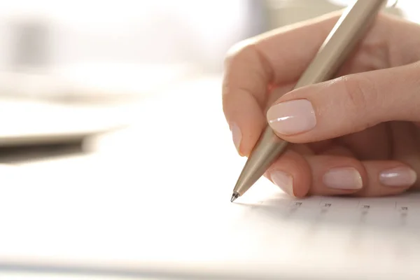 靠近一个女人的手 用铅笔在桌上填写表格 — 图库照片