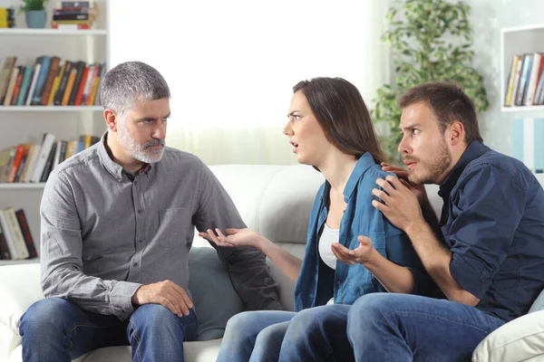 生气的父亲和女儿谈论害怕的男朋友坐在家里的沙发上 — 图库照片