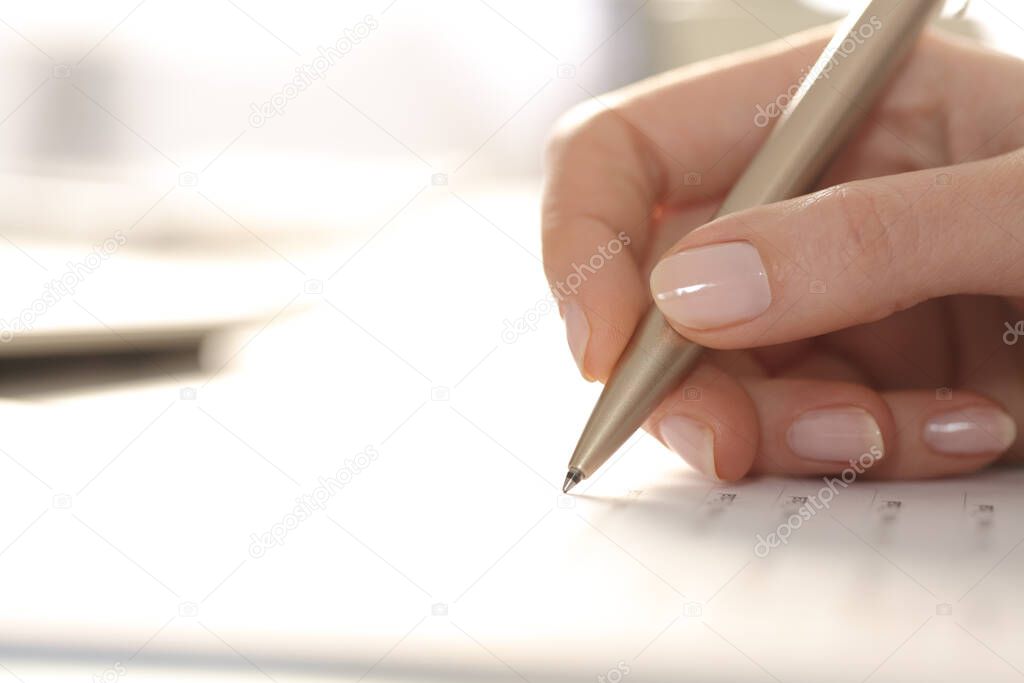 Close up of woman hand filling out form with pen on a desk