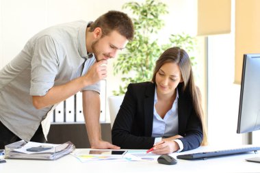 Ofisteki bir masada çalışan iki yönetici grafik raporlarına bakıyor.