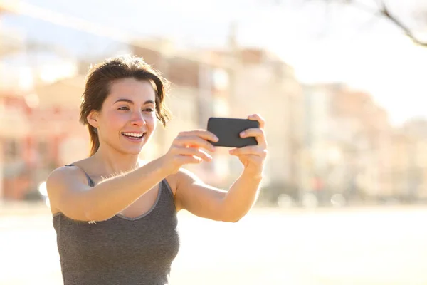 幸せな女性取ります自画撮りとともにスマートフォン笑顔でストリート — ストック写真