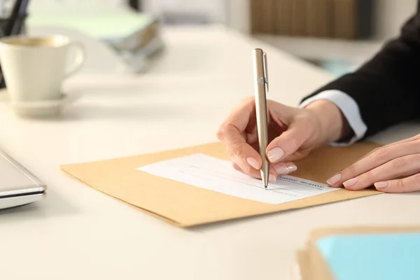 Close up of business woman hand filling out bank check sitting on a desk at the office