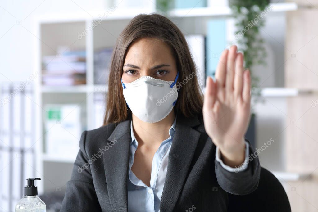 Front view of executive woman wearing protective mask doing stop gesture at the office