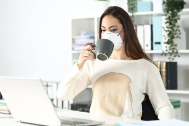 Girişimci kadın koruyucu maske takıyor ve gömleğinin üstüne kahve dökülüyor.