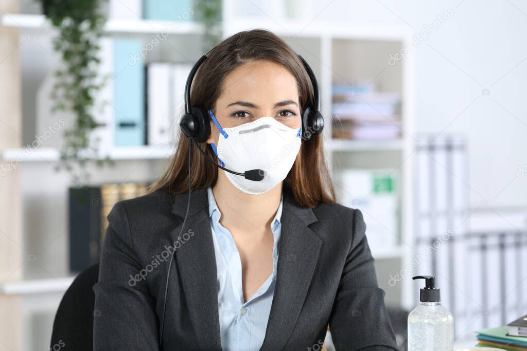 Happy telemarketer woman posing looking at camera avoiding covid-19 with mask sitting at the office