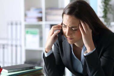 Akşamları ofis masasında oturan üzgün yönetici kadın akıllı telefondan arıyor.