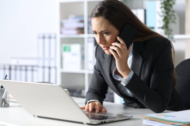 Endişeli yönetici kadın akıllı telefondan arıyor bilgisayarını kontrol ediyor ofisindeki masasında oturuyor.