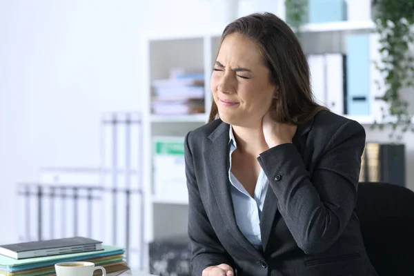 Executive woman with neckache complaining sitting on a desk at office