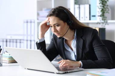 Üzgün pazarlamacı kadın laptopta kötü haberler okuyor. Ofisteki bir masada oturuyor.
