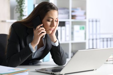 Dizüstü bilgisayarı olan sıkıcı bir yönetici ofisteki masasında oturmuş akıllı telefondan arıyor.