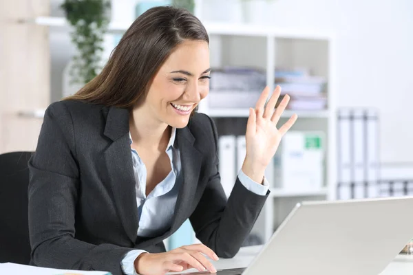 ハッピーエグゼクティブ女性挨拶上のビデオコール上のラップトップ座っています彼女の机の上にオフィス — ストック写真