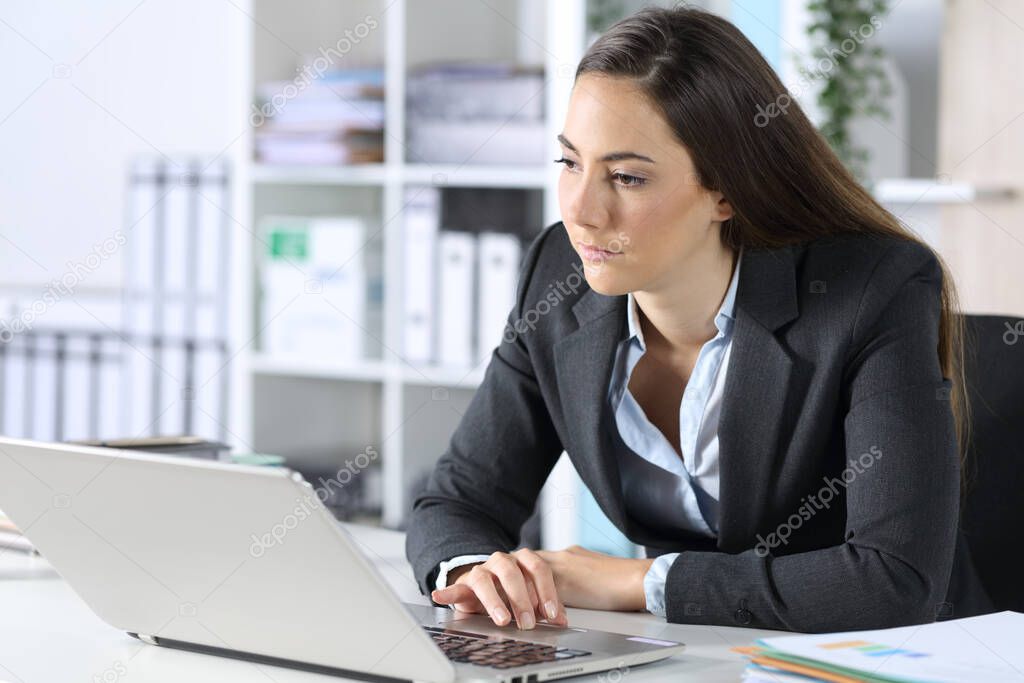 Distracted executive woman with laptop looking away sitting on her desk at the office