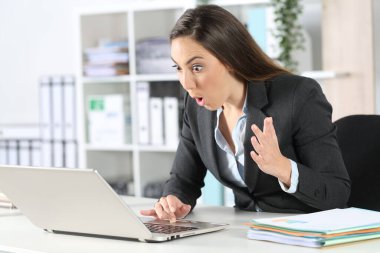 Bilgisayarda iyi haberler okuyan harika bir yönetici kadın ofisteki bir masada oturuyor.