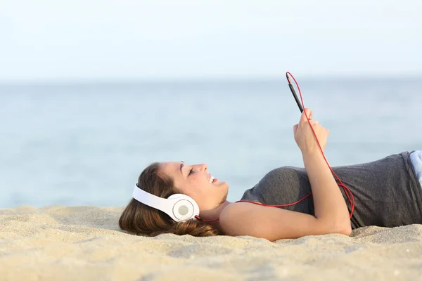 Side View Happy Girl Listens Music Smarphone Headphones Lying Sand — стоковое фото