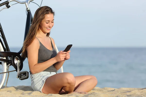 Menina Feliz Com Bicicleta Usando Telefone Inteligente Sentado Areia Praia — Fotografia de Stock