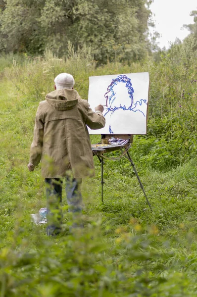 Starszy mężczyzna interesuje się malarstwem farbami olejną. Rysowanie krajobrazu naturalnego — Zdjęcie stockowe