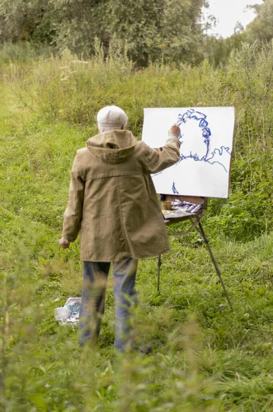 Yaşlı bir adam yağlı boyalarla resim yapmak istiyor. Doğal bir manzara çizimi