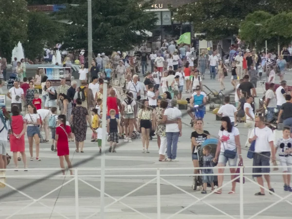 İnsanlar güneşli bir günde şehir boyunca yürür.