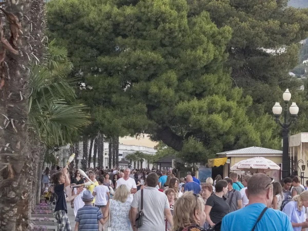 İnsanlar güneşli bir günde şehir boyunca yürür.