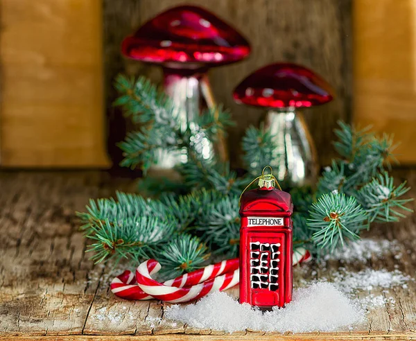 Christmas baubles Phone booth, mushrooms, candy cane Santa sticks and fir branch on the vintage wooden table. Christmas and New Year composition. Stock Image