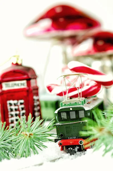 Vintage Spielzeugeisenbahn, Christbaumkugeln Telefonzelle, Pilze, Zuckerrohr-Weihnachtsmänner und Tannenzweig auf dem Vintage-Holztisch. Weihnachts- und Neujahrskomposition. — Stockfoto