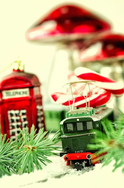 Vintage toy train, Christmas baubles Phone booth, mushrooms, candy cane Santa sticks and fir branch on the vintage wooden table. Christmas and New Year composition.