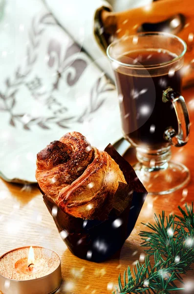 Coffee and cinnamon apple swirl (cruffin - mix of croissant and muffin), lit candle, snow, bokeh