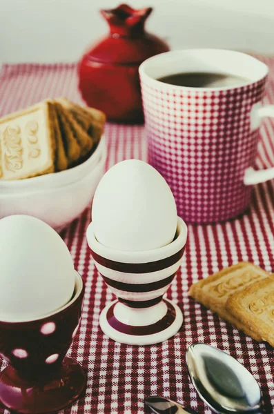 Hartgekochte Eier, Tee und Kekse werden in dem rot-weiß-rot-gestreiften Geschirr serviert — Stockfoto
