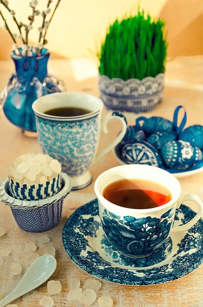 Easter morning with tea, sugar, eggs, daffodils, pussy-willow, mint and germinating seeds in blue color — Stock Photo, Image