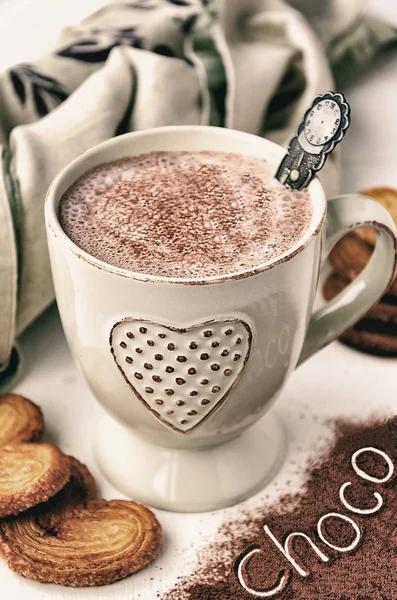 Hot cocoa with cream, heart shaped puff pastry and text "choco" over cocoa powder — Stock Photo, Image