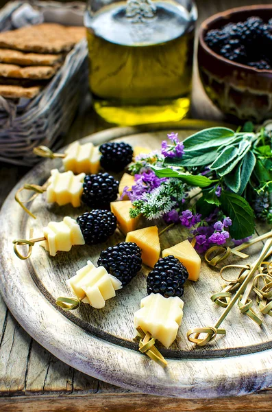 Blackberry and cheese sticks with herbs: lavender, sage, mint served on the vintage wooden table with olive oil and wholegrain crispbreads