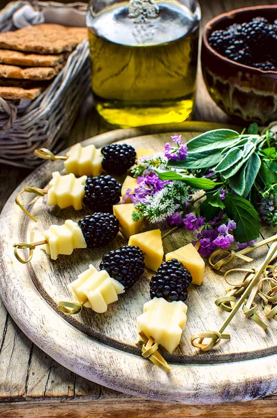 Blackberry and cheese sticks with herbs: lavender, sage, mint served on the vintage wooden table with olive oil and wholegrain crispbreads
