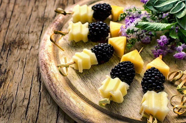 BlackBerry och ost pinnar med örter: lavendel, salvia, mynta serveras på tabellen vintage trä Stockbild
