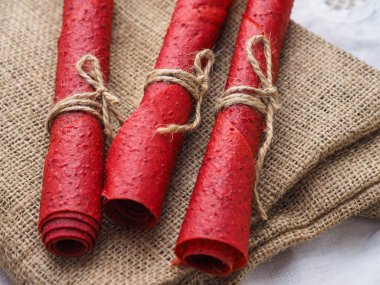 Kahverengi çuvalın üzerinde kırmızı çilekli rulo var.