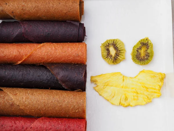 Цветные фруктовые кожаные роллы на белом фоне и фруктовая улыбка — стоковое фото