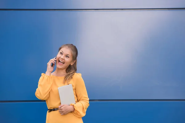 Souriant jeune femme d'affaires sur le téléphone tenant tablette — Photo