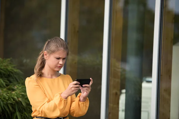 Joven mujer de negocios jugando con el teléfono celular — Foto de Stock