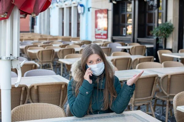 Koruyucu Maskeli Ciddi Bir Genç Kadın Boş Kafenin Terasında Oturuyor — Stok fotoğraf