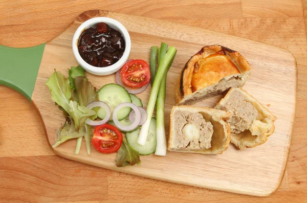 Pork pie and salad on chopping board