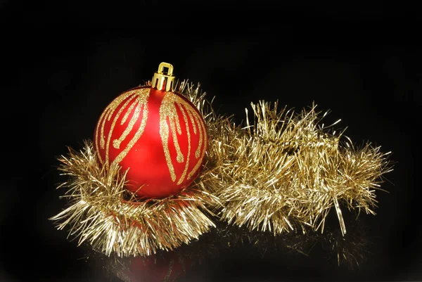 Christmas bauble and tinsel against black — Stock Photo, Image