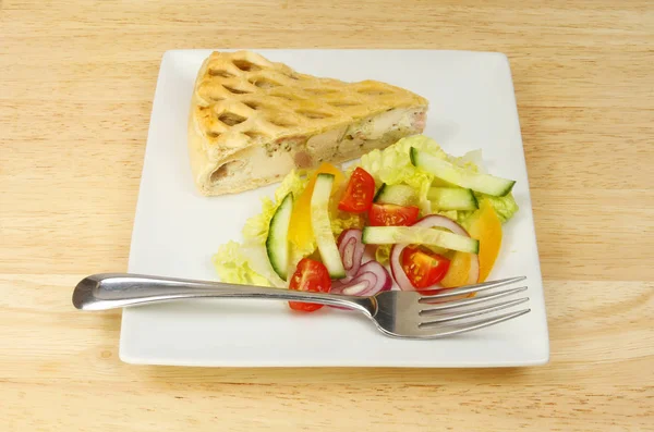 Hühnerkuchen und Salat auf einer Tischplatte — Stockfoto