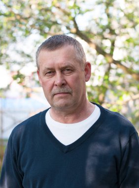 Güneşli bahar gününde arka bahçesinde bıyığı olan yakışıklı, orta yaşlı Avrupalı bir adamın portresi.