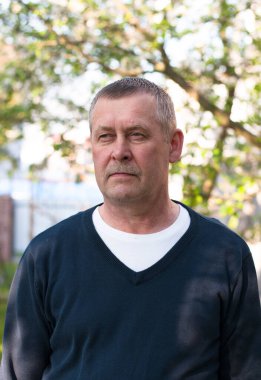 Güneşli bahar gününde arka bahçesinde bıyığı olan yakışıklı, orta yaşlı Avrupalı bir adamın portresi.